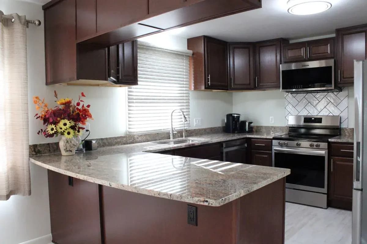 Finished kitchen remodel in Buffalo, Wyoming with dark wood cabinetry, peninsula, and stone countertops