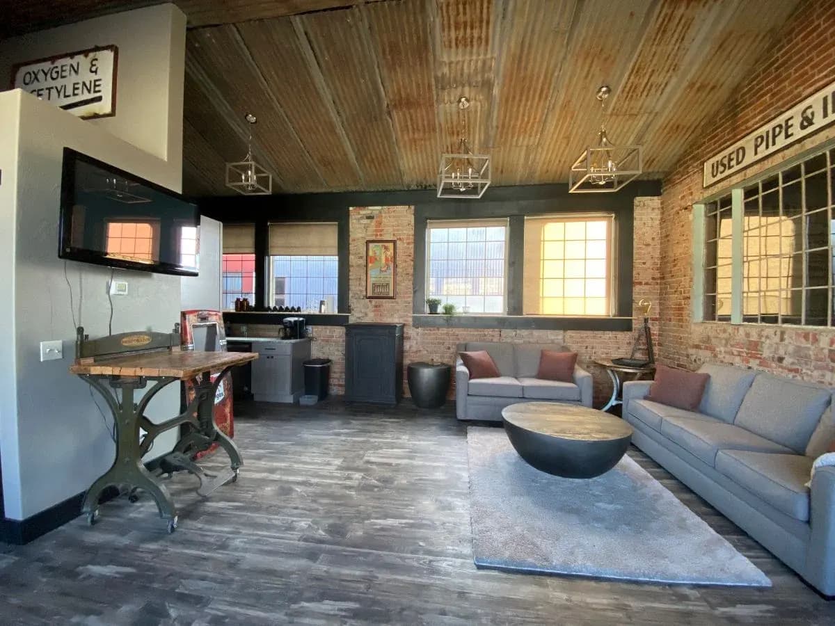 Remodeled living space with exposed brick, corrugated metal ceiling, and industrial pendant lighting