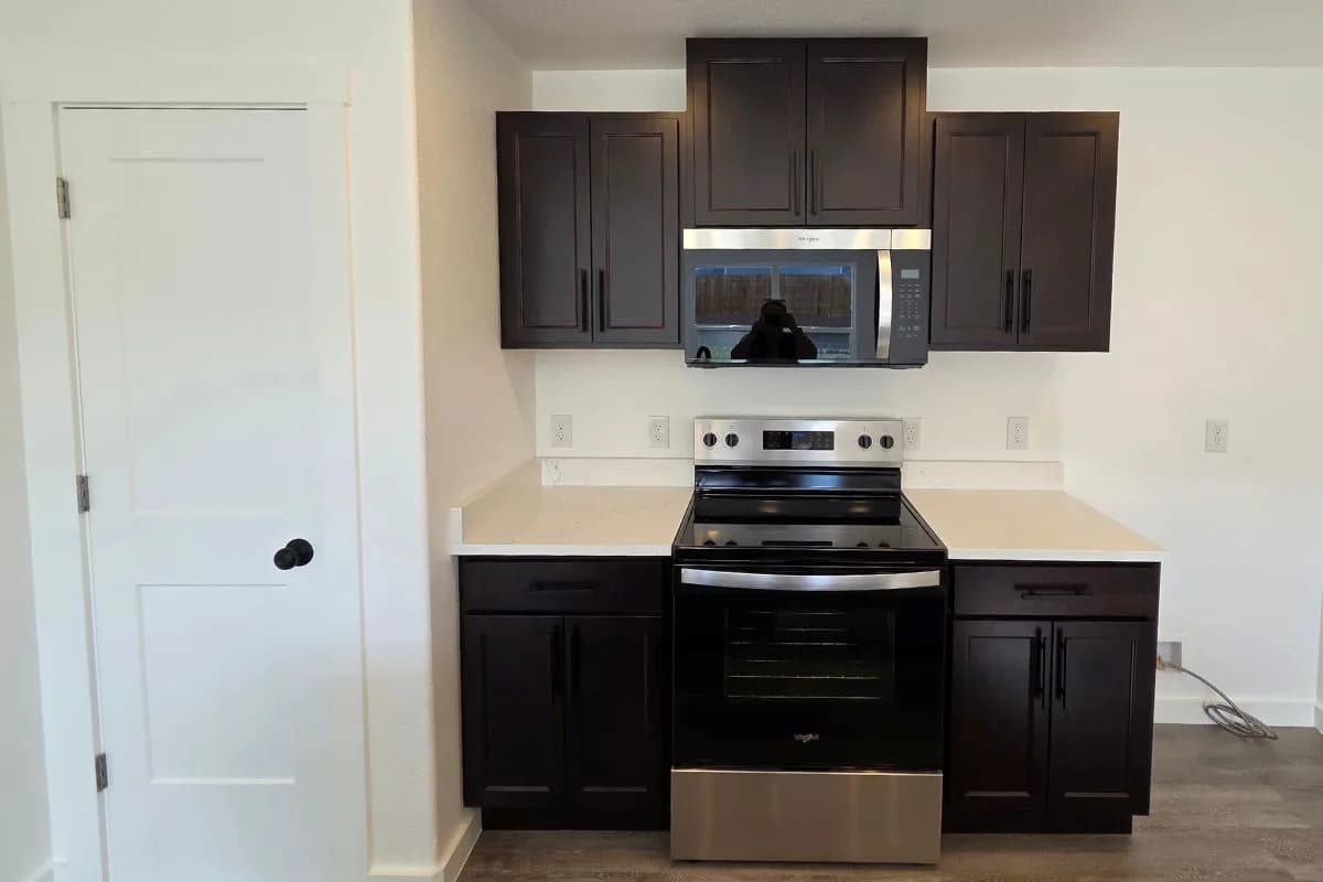 Dark kitchen cabinetry and appliances in the finished Tie Hack completed home