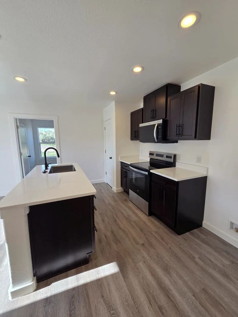 Kitchen with island and dark cabinetry in the finished Tie Hack completed home