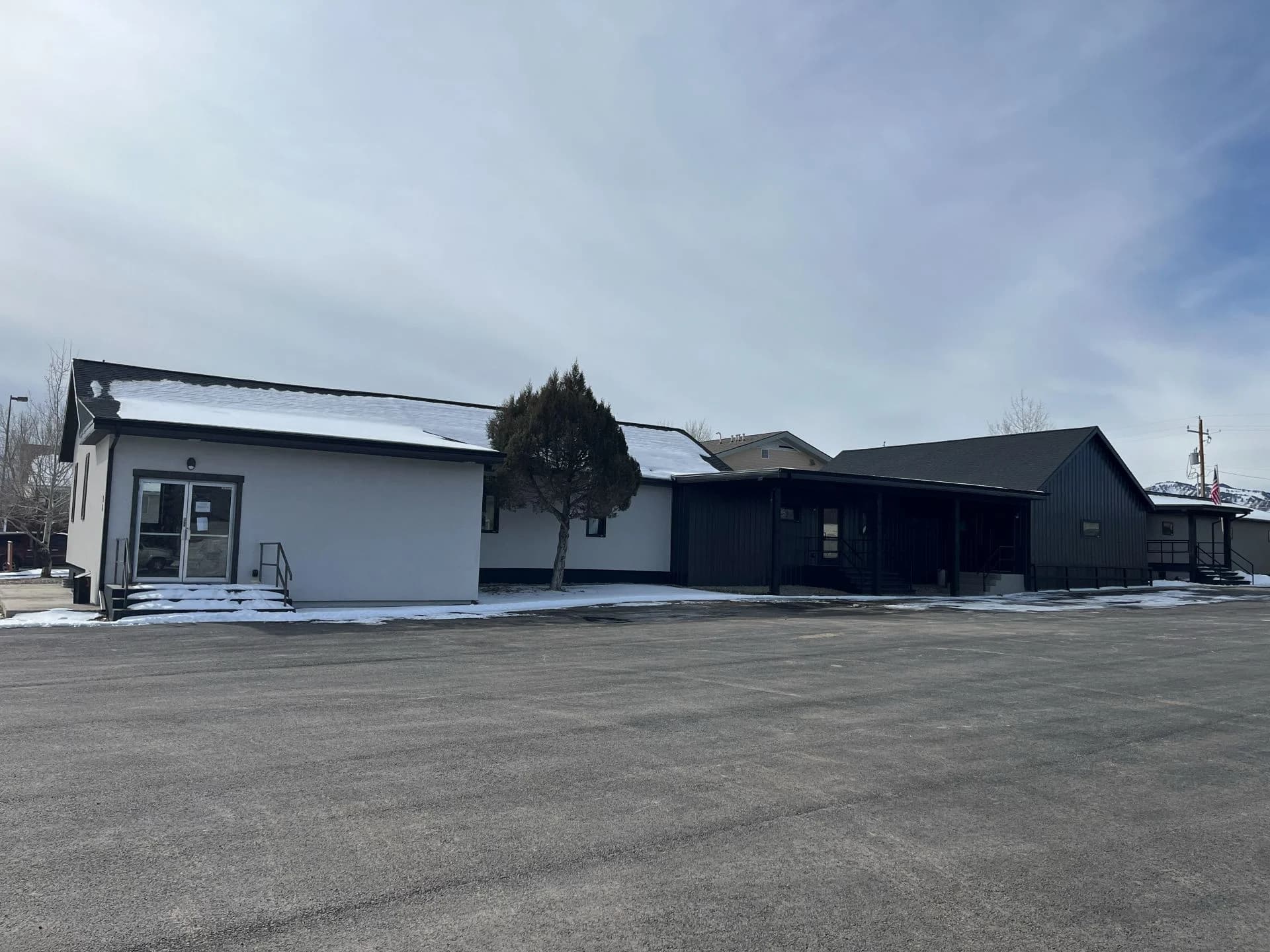 Finished exterior commercial remodeling project featuring modern dark metal siding and updated glass entry doors by Buffalo Built LLC.