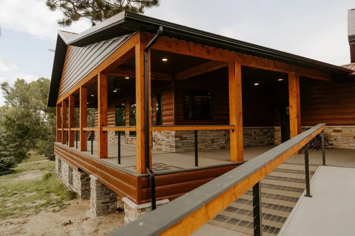Covered porch on a custom log home with timber posts and stone accents in Buffalo, Wyoming.